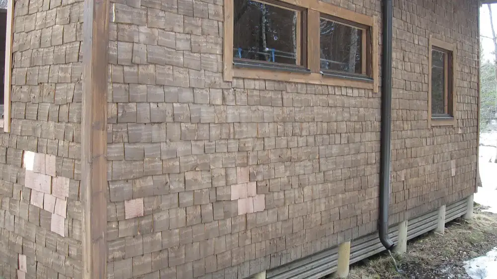 Close view of a home's exterior siding and caulked window trim from the ground