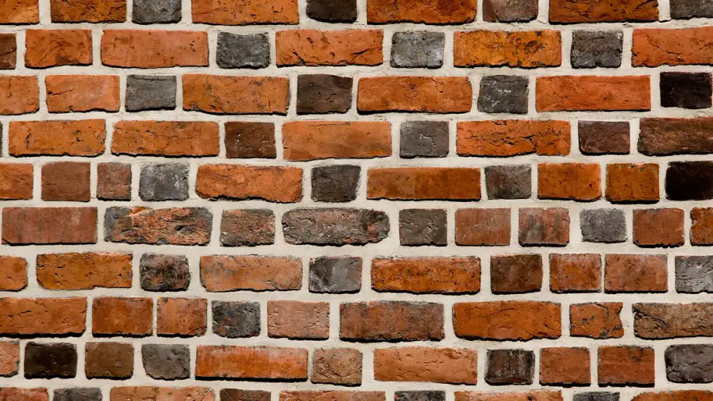 Close-up of a weathered red brick exterior wall with mortar joints