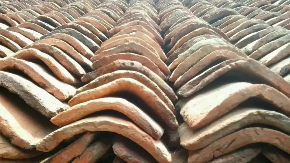 Rows of terracotta clay roof tiles on a residential roof under clear sky