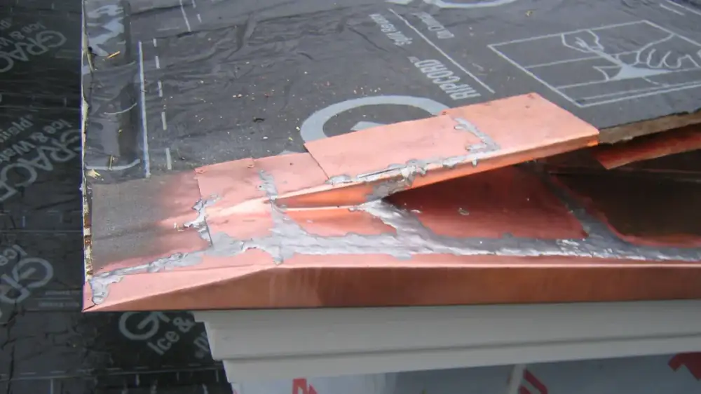 Copper half-round gutter with a warm brown patina along a roof edge