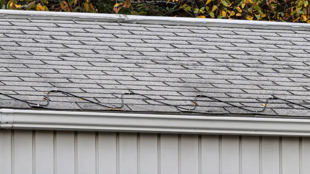 Icicles and an ice dam forming along a roof edge above a guarded gutter