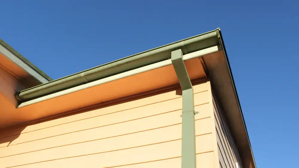 A house showing gutters on the sloped eaves and bare gable ends without gutters