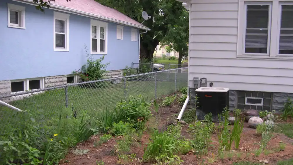 Downspout discharging a stream of water directly against a house foundation