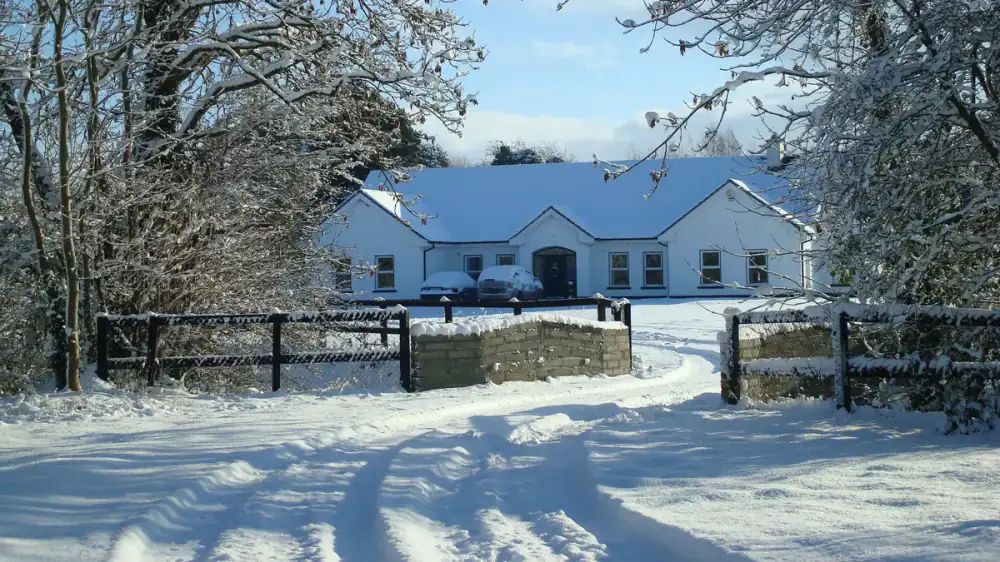 A home exterior with snow on the roof and ice forming at the gutters
