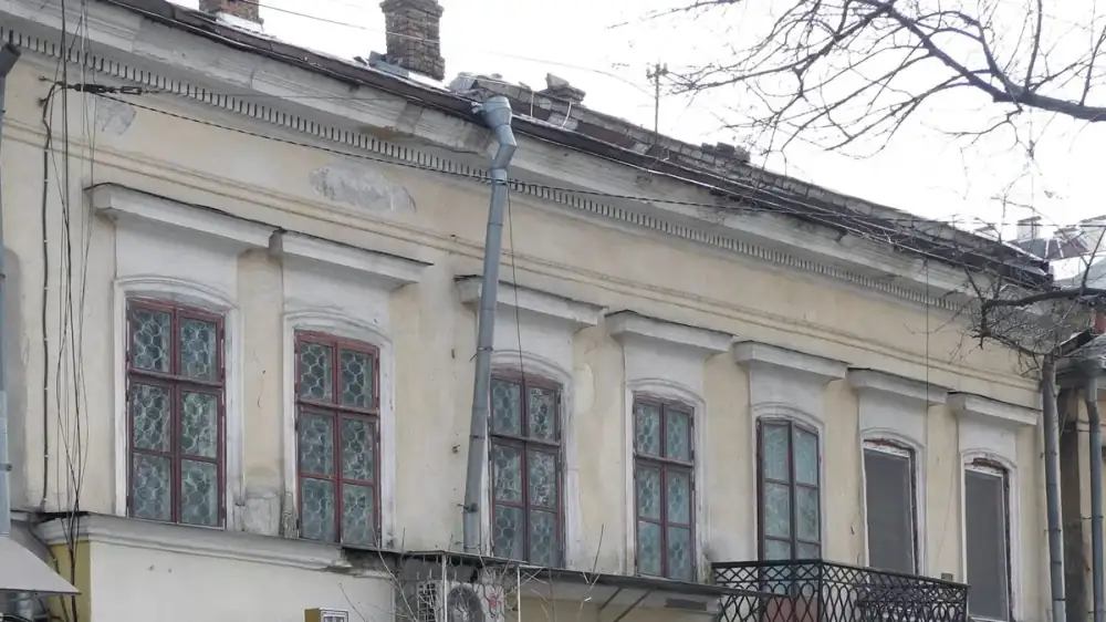 The upper-story roofline and gutters of a two-story house seen from the yard