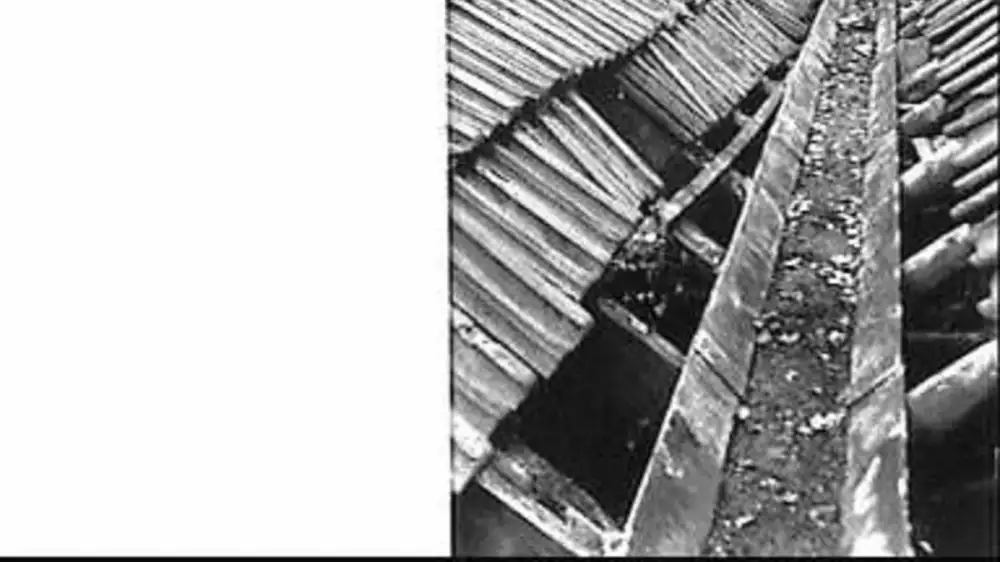 A metal splash guard fitted at the inside corner of a roof-edge gutter