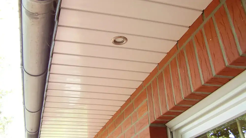 Rainwater draining cleanly from a roof edge into a home's gutter and downspout