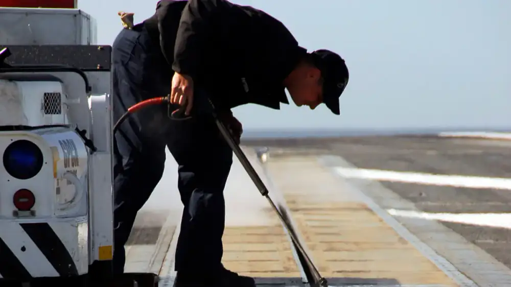 Pressure washer cleaning a hard exterior surface with a fan of water