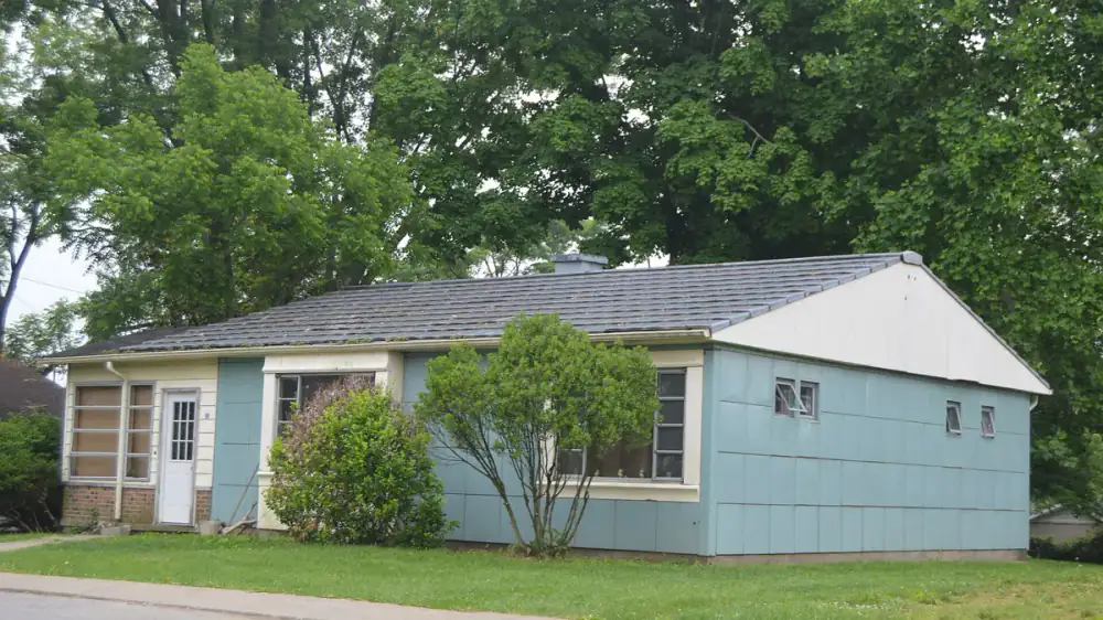 A homeowner reviewing a written scope of work with an exterior contractor at a house