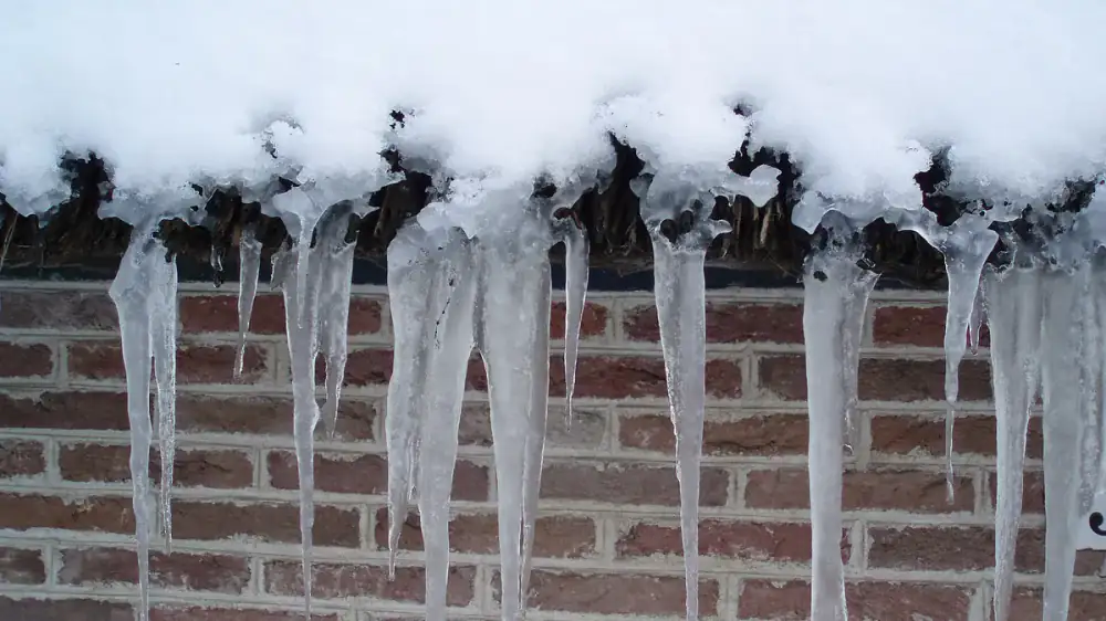 Self-adhering ice and water shield membrane installed along a roof eave