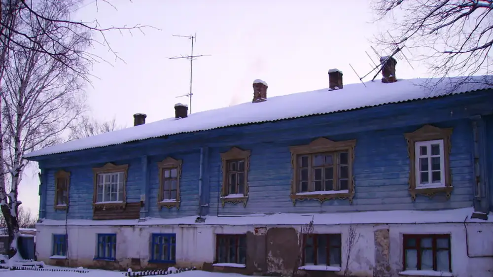 A home's roof edge with lingering ice and snow along the gutters in late winter