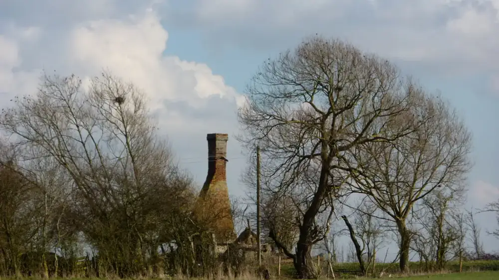 A masonry chimney visibly leaning away from the roofline of a house