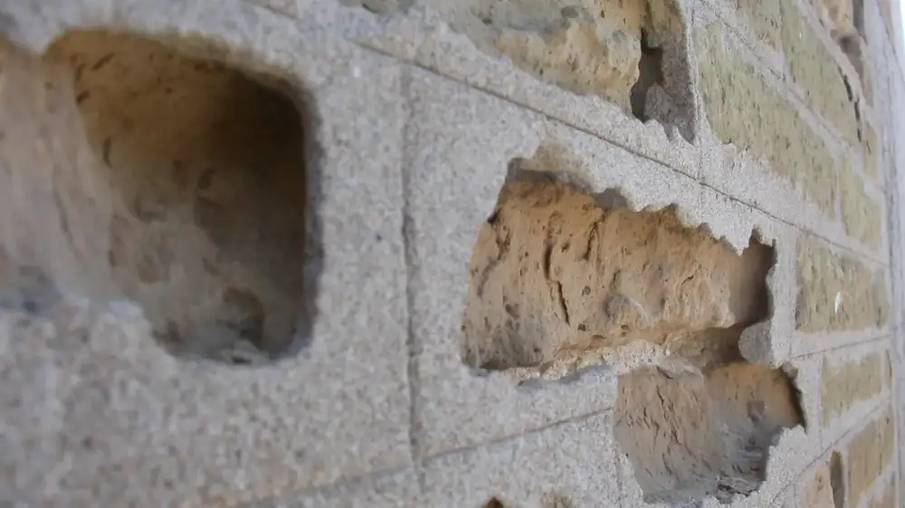 A brick wall with eroded mortar joints alongside a freshly repointed section
