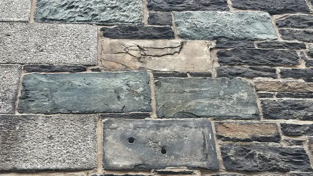 Natural stone veneer wall with varied gray and tan stone faces and mortar joints