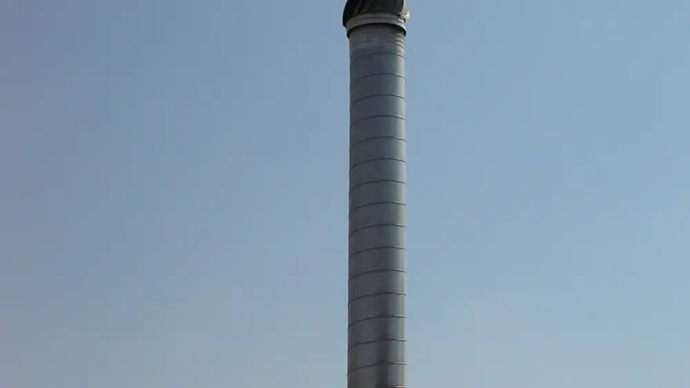 A rusted metal chimney cap with orange rust streaks on the masonry below