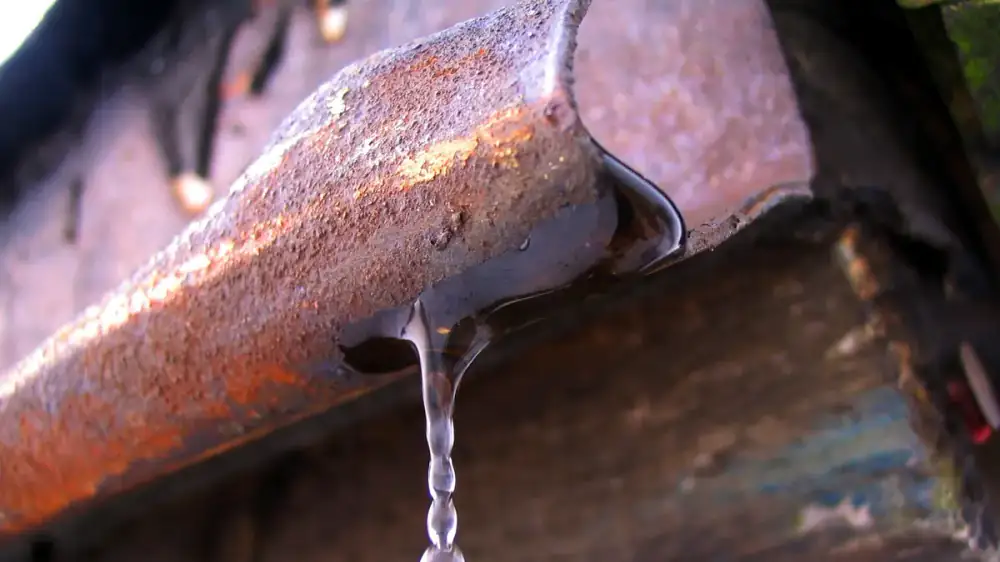 A warped and rusted gutter guard section showing signs of age