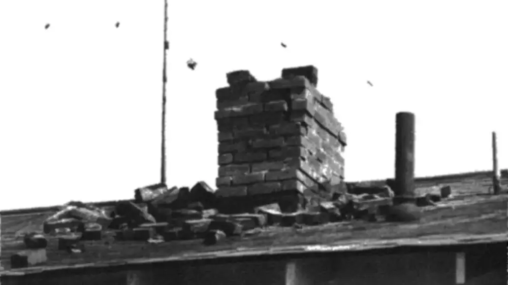 A chimney under repair with scaffolding against the side of a house