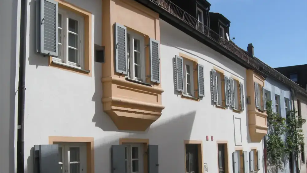 The lower edge of a house roof showing fascia board, soffit and gutter against a blue sky