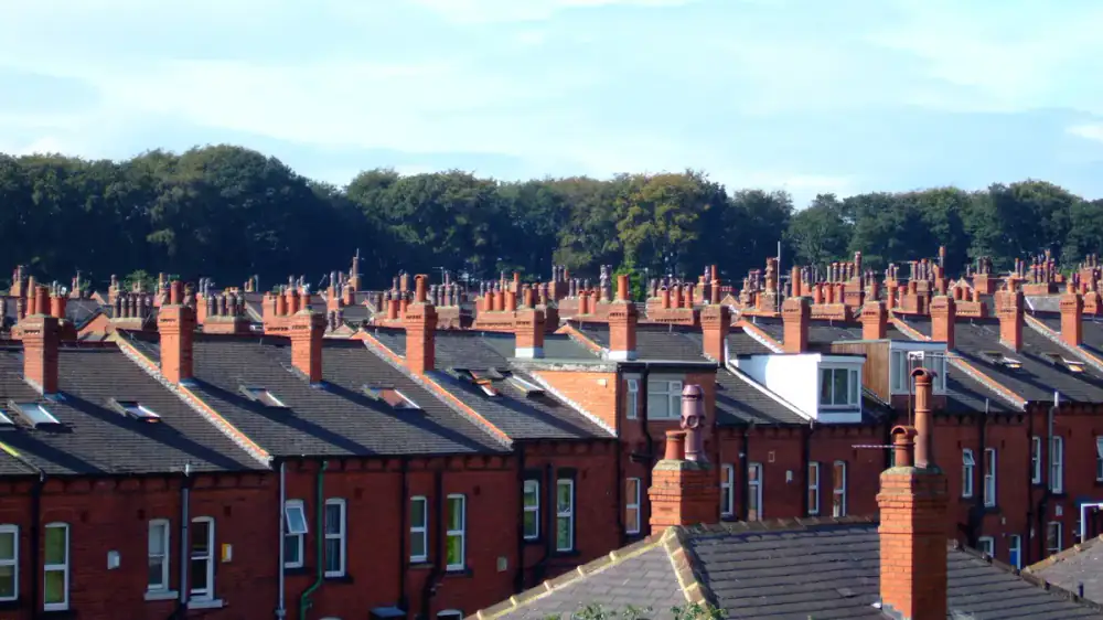 A metal chase cover on top of a sided prefab chimney chase against a blue sky
