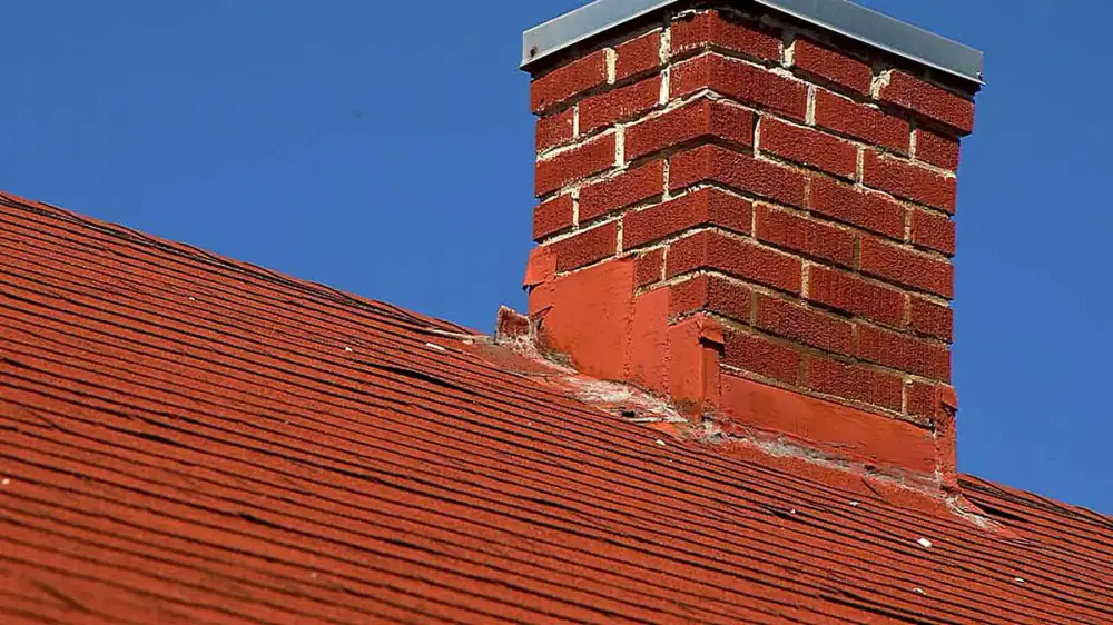 The concrete crown at the top of a brick chimney with a flue and cap