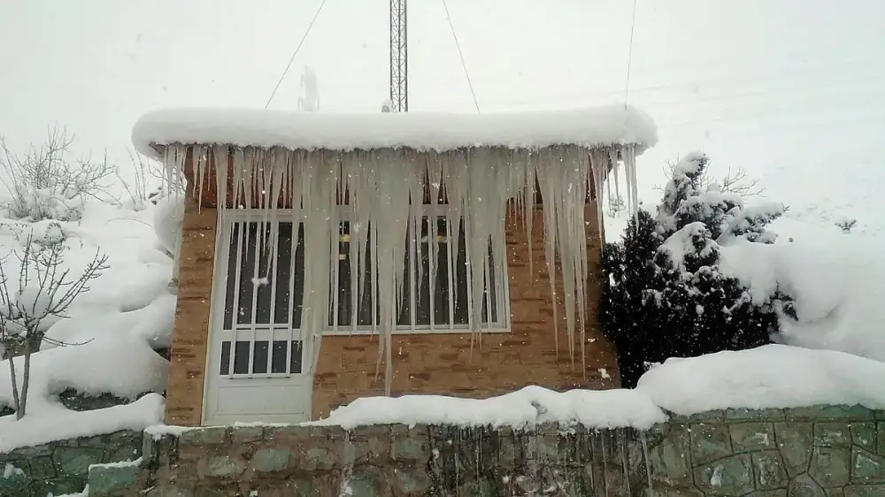 Icicles hanging from a snow-covered roof edge above a walkway