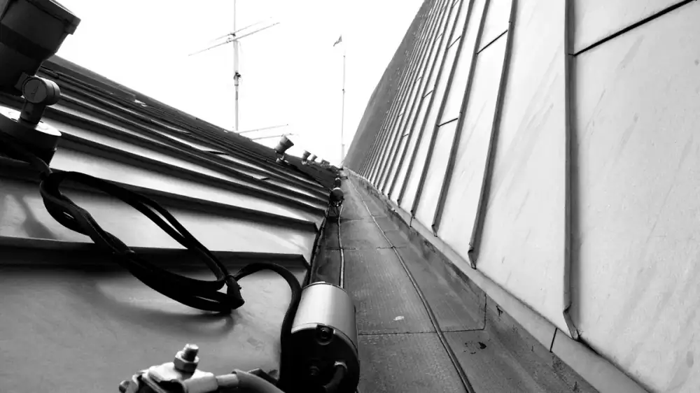 Zinc half-round gutter along a roof eave with a soft gray-blue patina